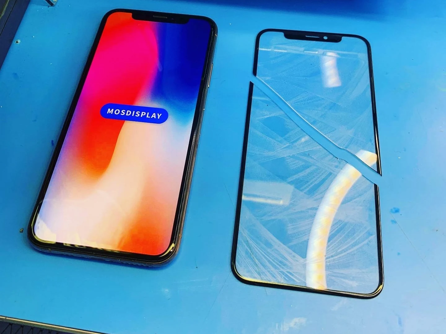 Включённый iPhone и отдельное треснувшее стекло на рабочем коврике