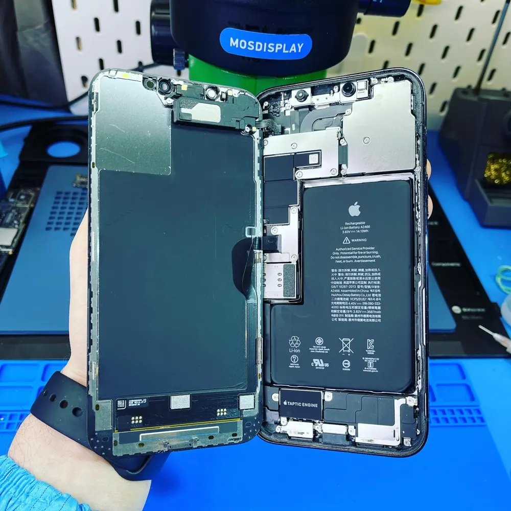 Вскрытый iPhone с аккумулятором на столе мастера