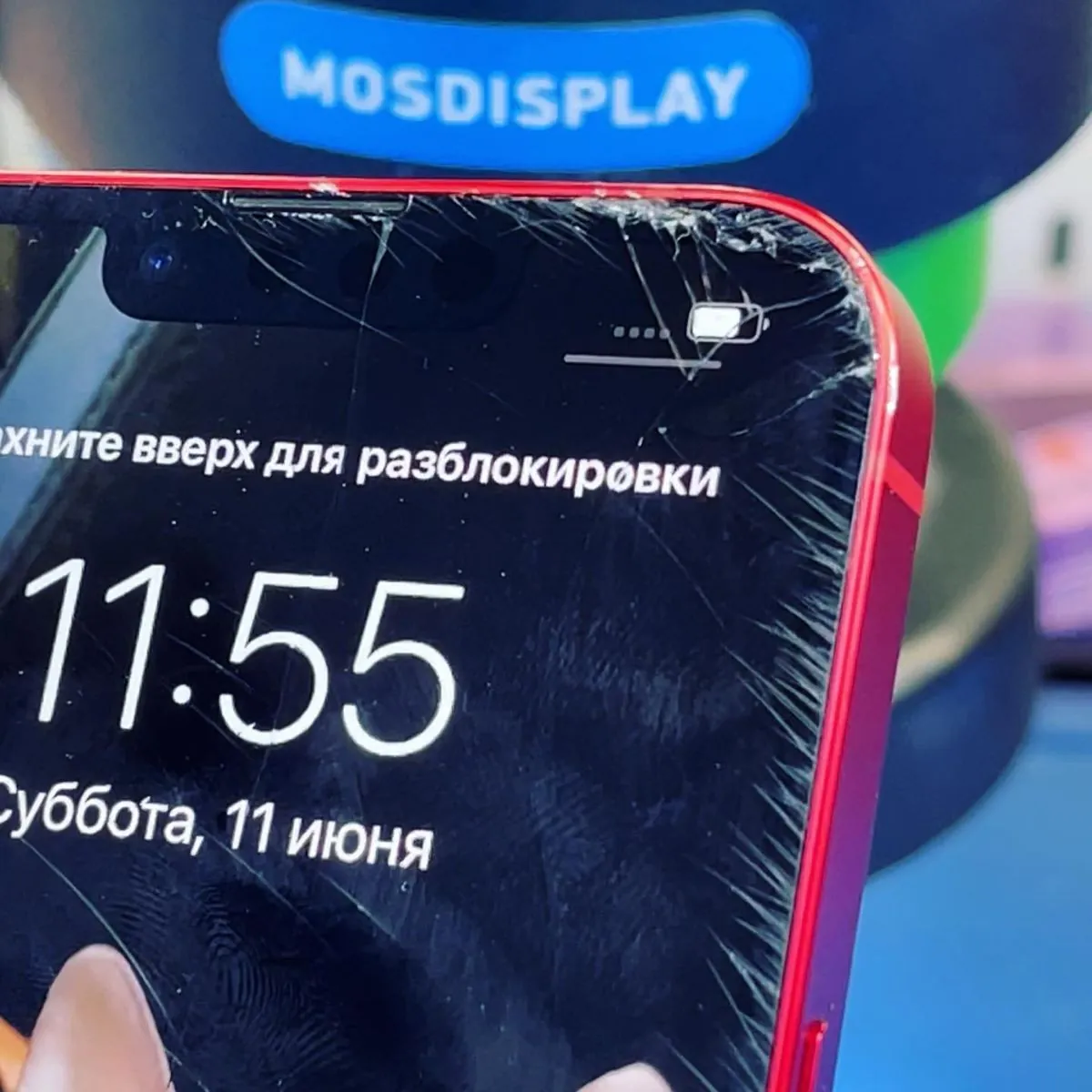 Угол iPhone 13 с трещинами на стекле, изображение под ними светится ровно