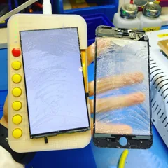 Экран iPhone после снятия разбитого стекла проверяют на тестере, рядом — снятое стекло