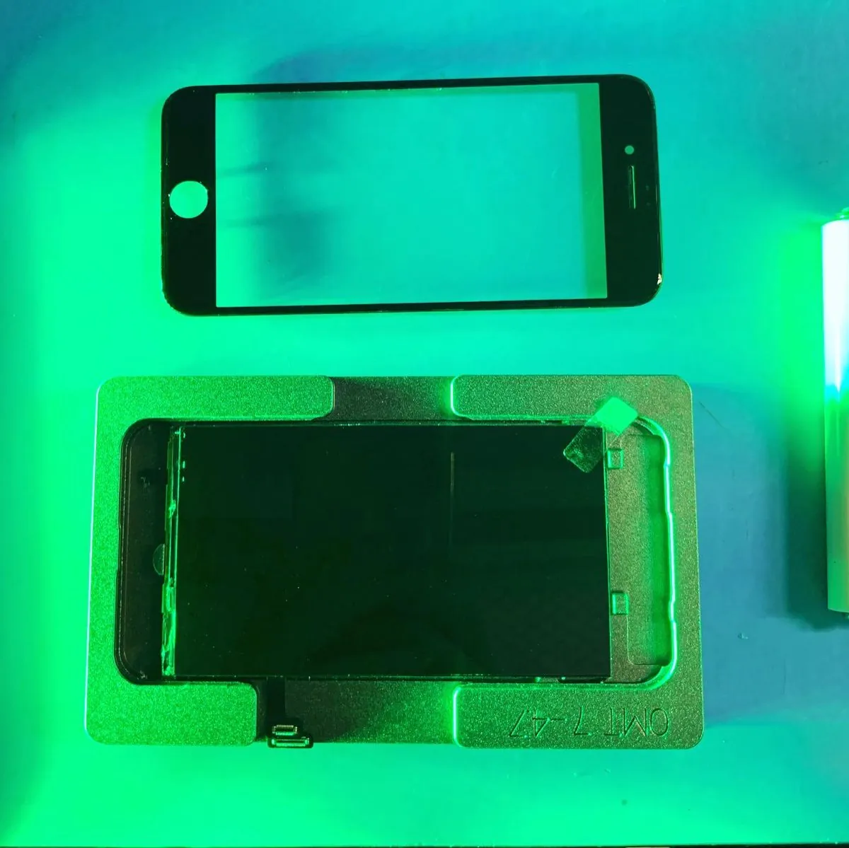 Экран iPhone 7 или 8 в форме для центровки, рядом новое стекло