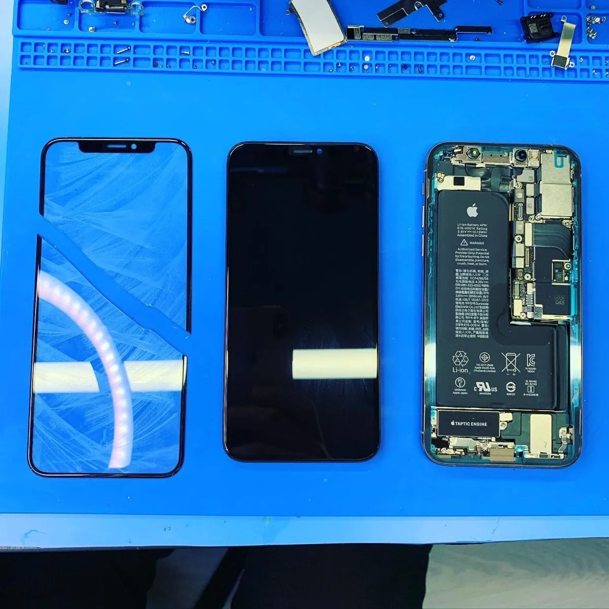 Новое стекло, экран и вскрытый корпус iPhone X или XS на столе мастера